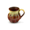handmade ceramic tea cup with a round shape and a handle, in orange red with green ash drips, on white background