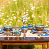 spring outdoors table setting, including a ceramic bud vase, stoneware mugs, dinner plates, lunch plates, and cereal bowls